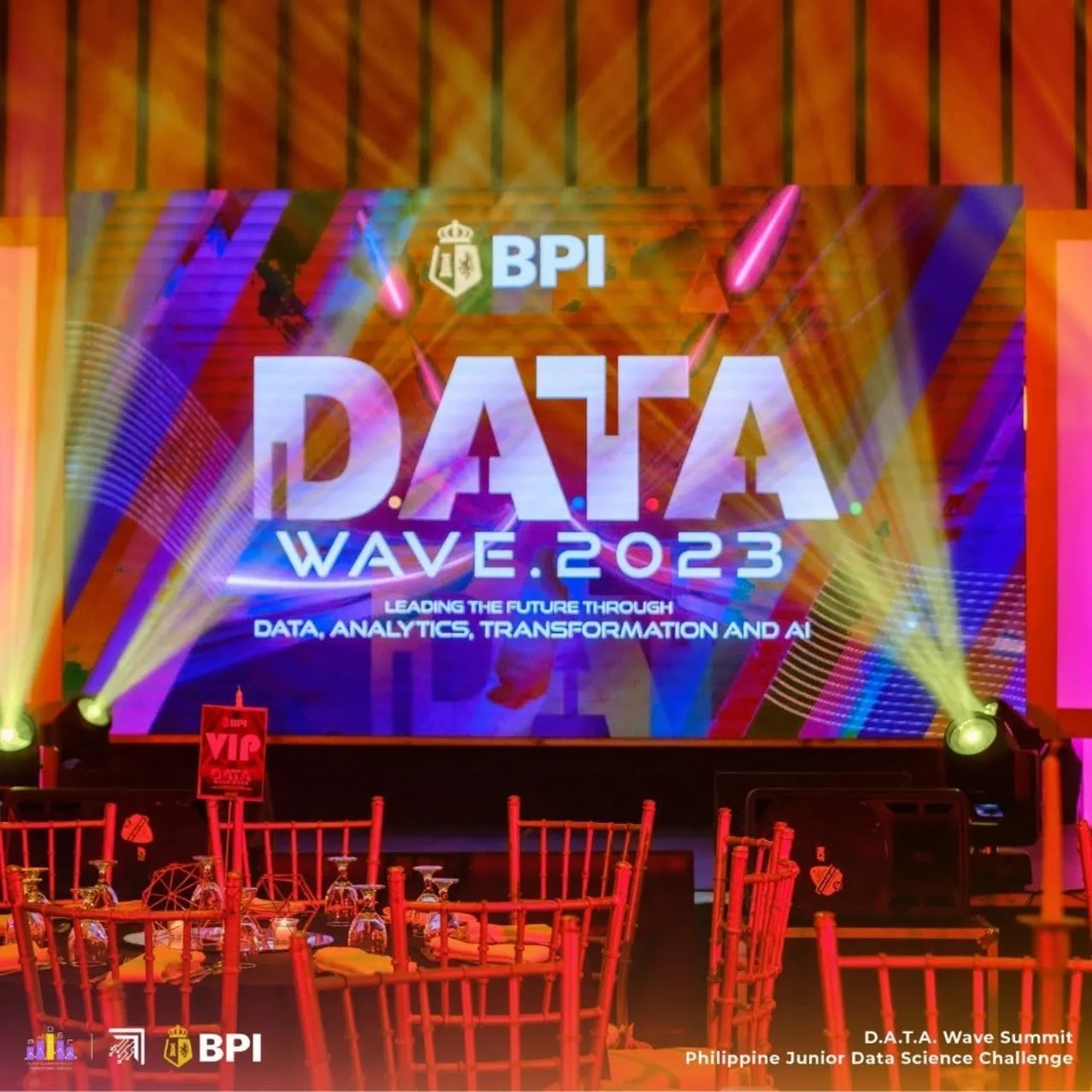 The BPI DATA Wave 2023 stage at One Esplanade, with the summit title on a large screen above rows of red chairs and round tables.