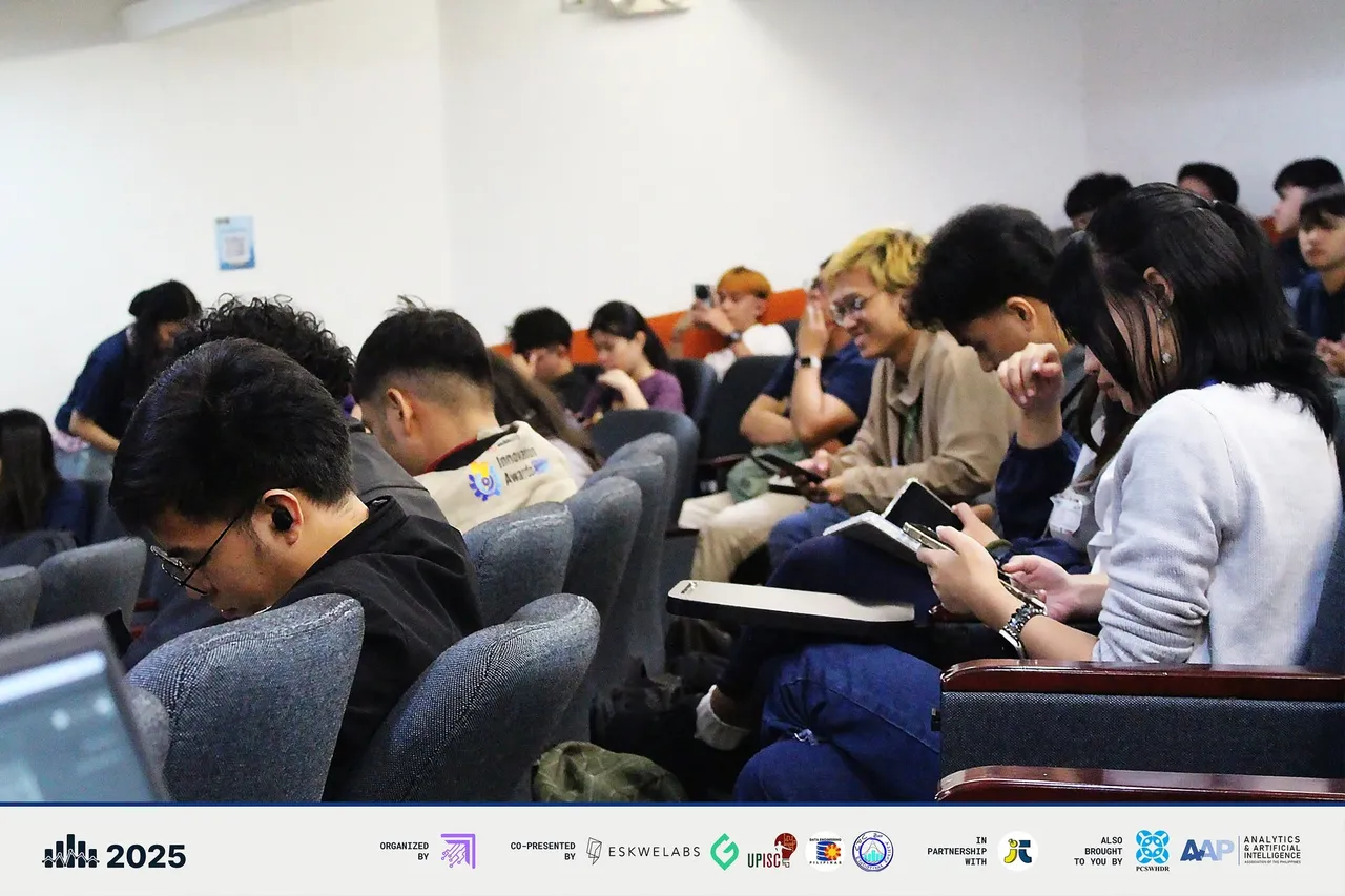 Finalists and guests in the auditorium seats reviewing notes and laptops between presentations.