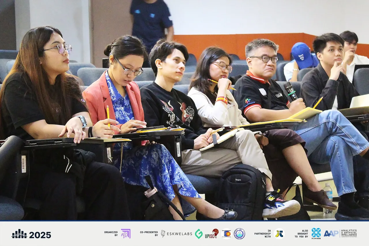 The panel of judges seated in the front row taking notes during a presentation.